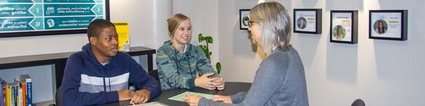 Janelle Andrineini sits across from a female and male student in the Career Center.